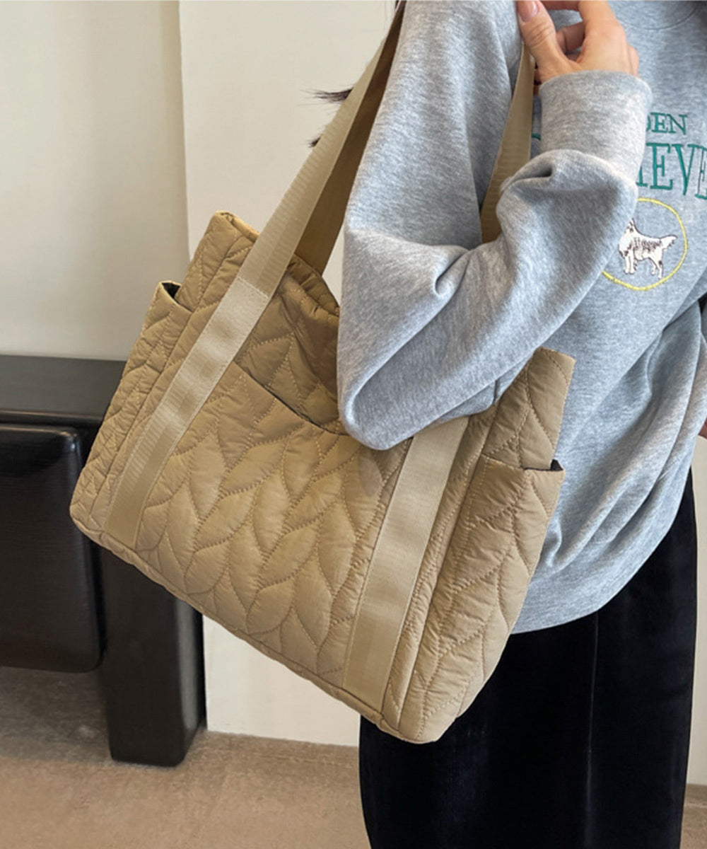 グレーのスウェットを着た女性が持つ、軽量で旅行や日常使いにぴったりのベージュのキルティングトートバッグ。シンプルで機能的なデザインが特徴で、肩にかけやすい長めのストラップが付いています。おしゃれで実用的なアイテムとして、20〜30代の日本人女性に人気。柔らかい素材で快適な使用感を提供し、ECサイトのSEO対策にも最適なキーワードを盛り込んでいます。